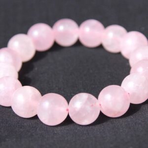 A Rose Quartz Bracelet is arranged in a circular shape on a black background.