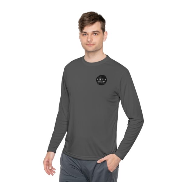 A person wearing an Unisex Lightweight Long Sleeve Tee with a circular logo on the left side of the chest.