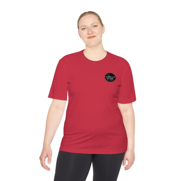 A person wearing a red Circle of Chi Athletic Tee and black pants is standing against a plain white background.