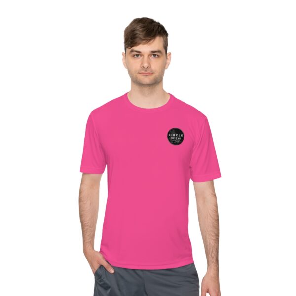 A man wearing a bright pink Circle of Chi Athletic Tee with a circular logo on the left chest stands with one hand in his pocket, set against a plain white background.