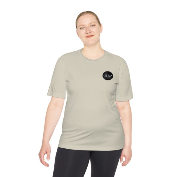 Person standing, wearing the Circle of Chi Athletic Tee with a small black circular logo on the left side and black pants, smiling slightly.