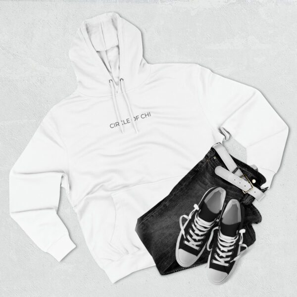 White Three-Panel Fleece Hoodie with "CIRCLE OF CHI" text, paired with dark jeans, white belt, and black sneakers with white laces, laid on a light grey surface.