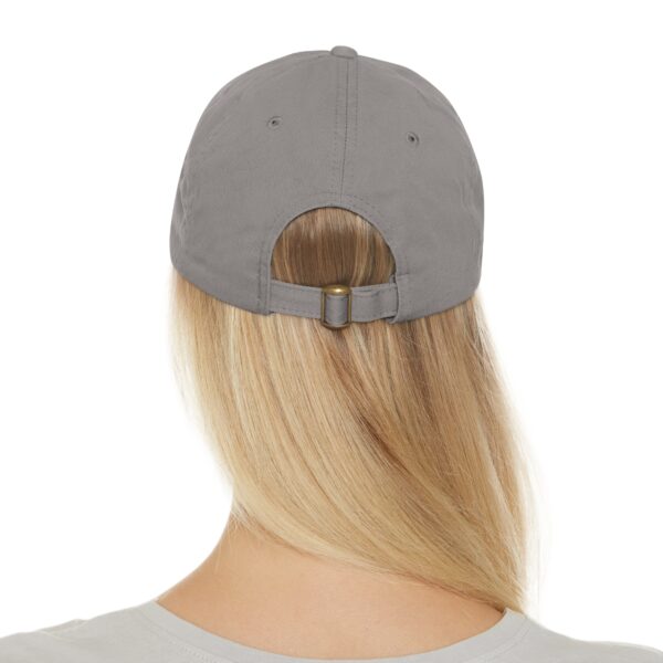 Rear view of a person with long, blonde hair wearing a Circle of Chi Dad Hat with Leather Patch, showing the adjustable strap at the back of the cap.