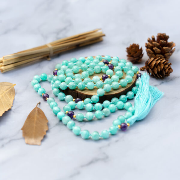 Teal gemstone mala with tassel on marble.